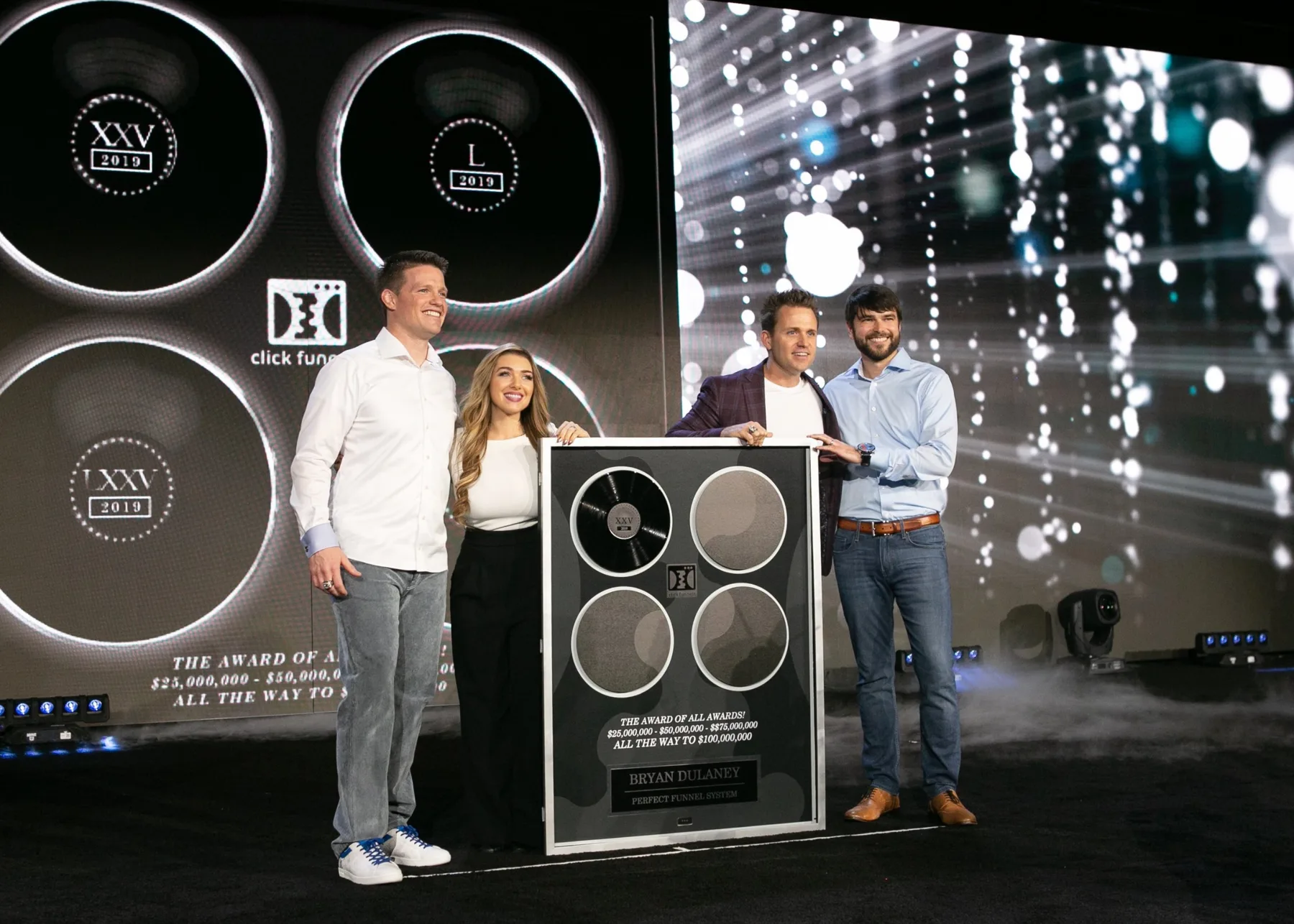 Bryan and Stephanie Dulaney on stage receiving the ClickFunnels Award of All Awards plaque for Perfect Funnel System