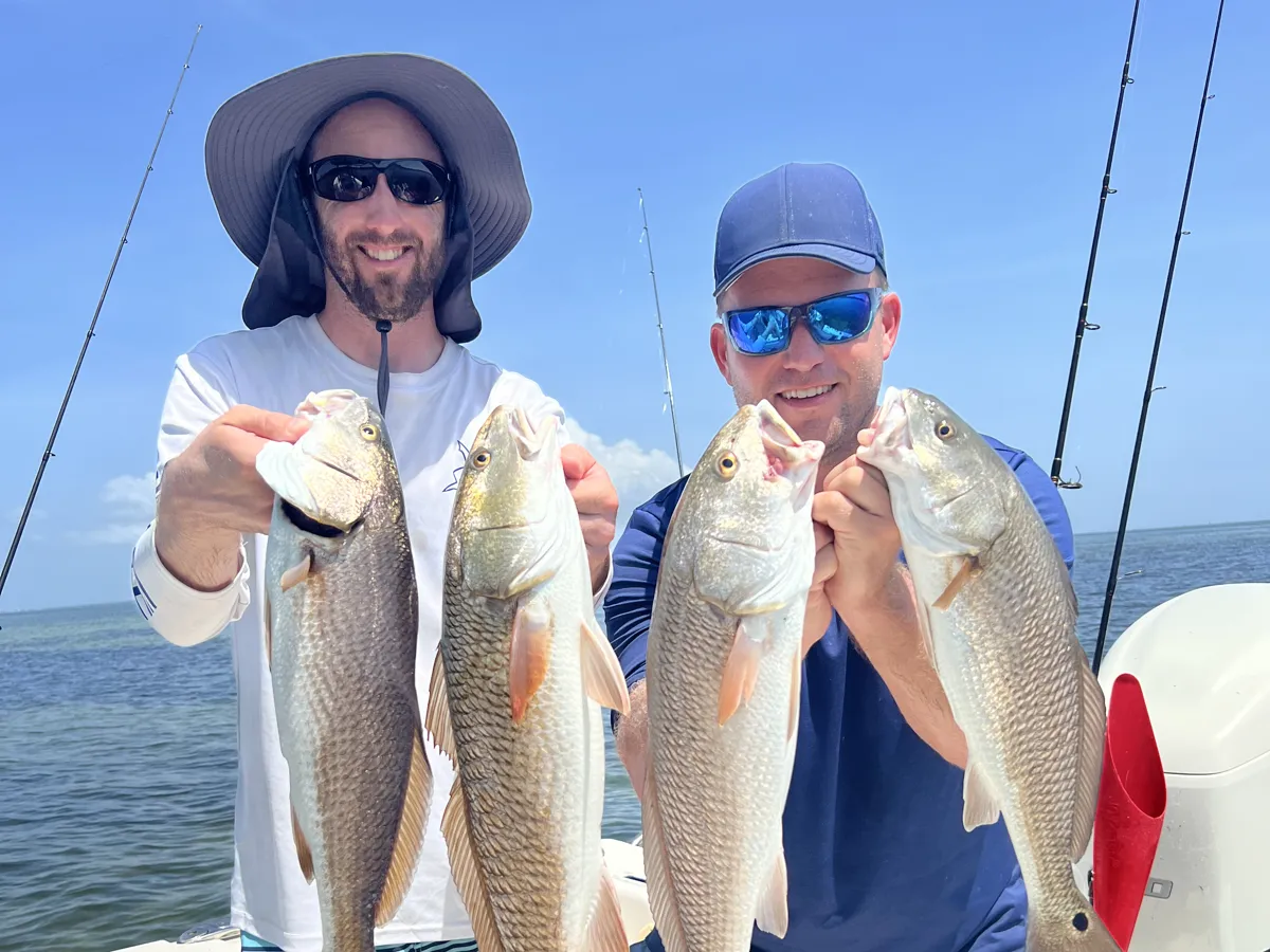 Bryan and his brother holding redfish on the boat